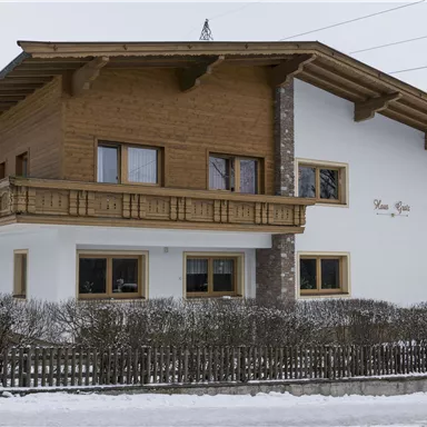 Ein schönes, modernes Haus mit Holz und Stein. Umgeben von Schnee und Bergen, vermittelt es eine gemütliche Atmosphäre.