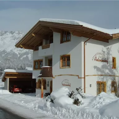 Ein malerisches Gebäude im alpinen Stil, umgeben von Schnee. Im Hintergrund sind Berge zu sehen.