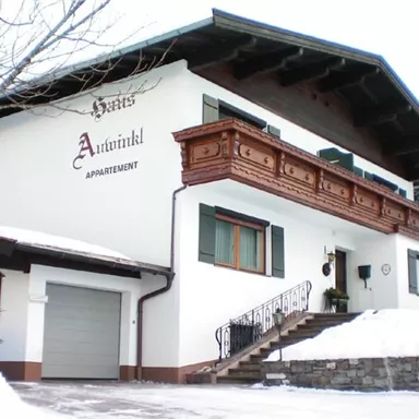 A beautiful chalet with traditional architecture in the snow. Surrounded by trees and a winter landscape.