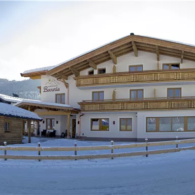 Ein charmantes Haus im alpinen Stil mit Holzverkleidung und einem Eingang. Schnee bedeckt die Umgebung und die Berge sind im Hintergrund sichtbar.