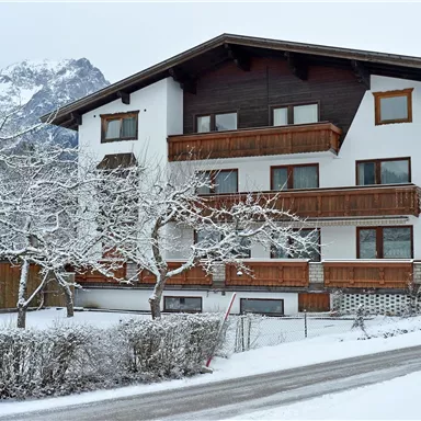 A charming building in winter, surrounded by snow-covered trees. The mountains in the background complement the idyllic landscape.