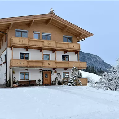 Ein schönes Haus im alpinen Stil, umgeben von schneebedeckten Bergen. Der Winter verleiht der Szene eine ruhige Atmosphäre.