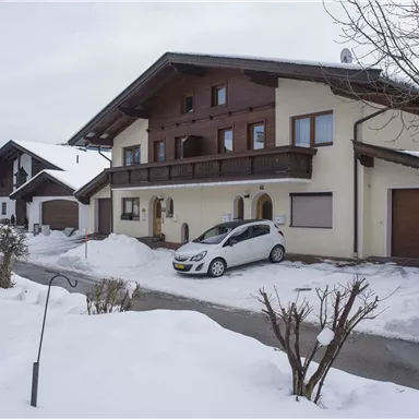 Ein modernes Haus im Schnee mit einem Auto davor. Die Umgebung ist winterlich und ruhig.