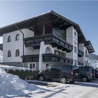 Ein modernes Gebäude im alpinen Stil, umgeben von Schnee. Der klare Himmel und die winterliche Landschaft verleihen der Szene eine ruhige Atmosphäre.
