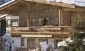 A cozy wooden house in the snow, surrounded by trees. The scene conveys a tranquil, wintry atmosphere.