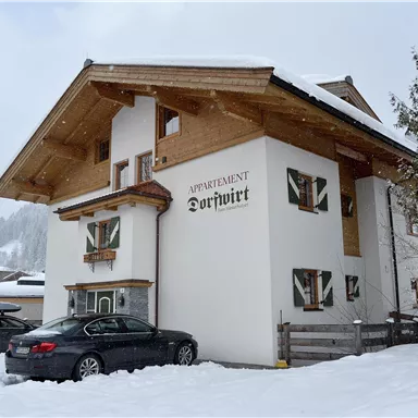 Ein charmantes Gebäude im Alpenstil, umgeben von Schnee. Parkplätze sind vor dem Haus vorhanden.