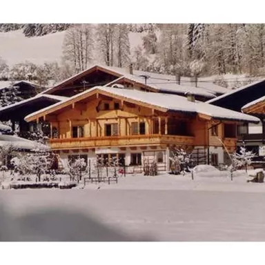 Ein charmantes Holzhaus in einer verschneiten Winterlandschaft. Umgeben von schneebedeckten Bäumen und Bergen.
