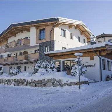 A cozy chalet in the snow, surrounded by trees. The sky is clear and the architecture is rustic.