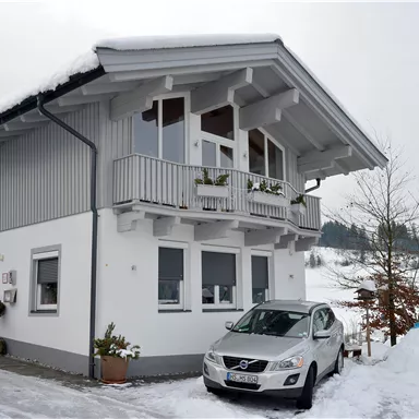 Ein schönes Haus im Winter mit Schnee bedeckt. Ein Pkw steht auf der Einfahrt vor dem Gebäude.