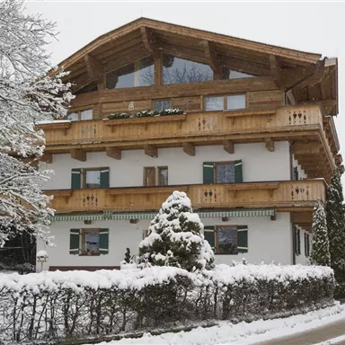 Ein charmantes Holzhaus im Winter, umgeben von frischem Schnee. Die Umgebung ist ruhig und idyllisch mit schneebedeckten Bäumen.