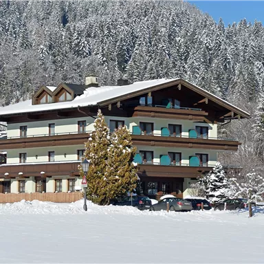 Ein charmantes Gebäude im Schnee, umgeben von schneebedeckten Bäumen. Der klare blaue Himmel vervollständigt die winterliche Atmosphäre.