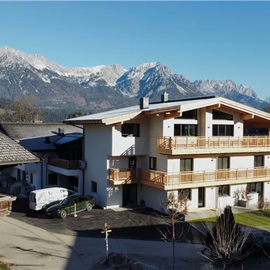 A charming house in the Alps with a beautiful mountain panorama in the background. The clear air and the blue sky give the scene a peaceful atmosphere.