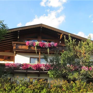 Ein charmantes Haus mit einem holzverkleideten Balkon. Bunte Blumen schmücken das Gebäude und die Umgebung.