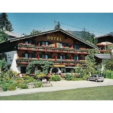 Ein traditionelles Hotel mit blühenden Balkonblumen. Umgeben von einer malerischen Berglandschaft.