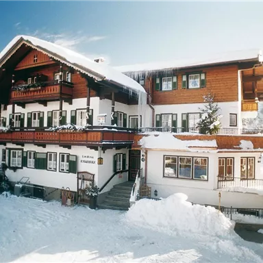 Ein charmantes Haus im klassischen Alpenstil, umgeben von Schnee. Die Atmosphäre ist gemütlich und einladend.