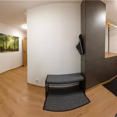 A modern entrance area with wooden flooring and two doors. A few pictures of trees are hanging on the wall.