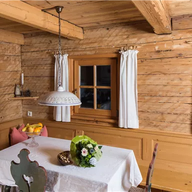 A cozy room with wooden paneling and a dining table. A flower vase and fresh fruit are on the table.