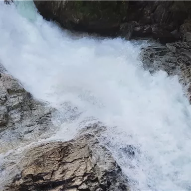 A wild waterfall flows over rocky cliffs. The water bubbles and creates a lively, sparkling atmosphere.