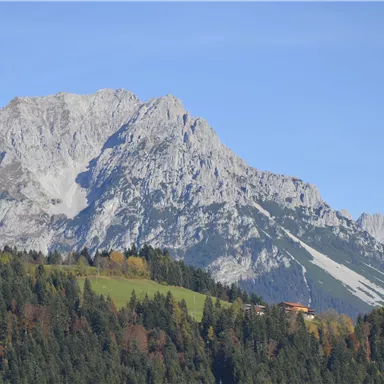 Ein beeindruckendes Bergpanorama mit schroffen Gipfeln und grünen Hängen. Der Himmel ist klar und die Landschaft strahlt Ruhe aus.