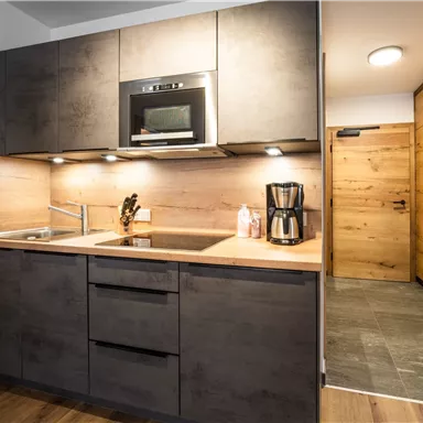 A modern kitchen with wooden paneling and functional appliances. The bright environment creates an inviting atmosphere.