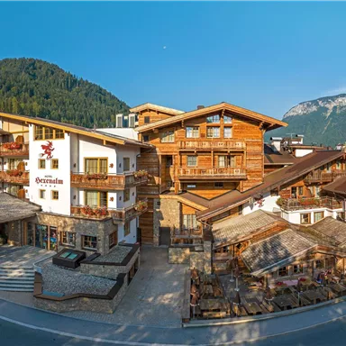 Eine malerische Alpinhütte mit rustikalen Holzbauten. Umgeben von grünen Bergen und klarem Himmel.