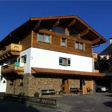 Ein traditionelles Holzhaus mit aufwendigen Balkonen. Das Gebäude hat eine Mischung aus Holz- und Steinarchitektur und steht unter klarem Himmel.
