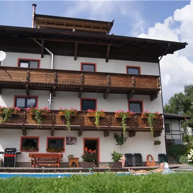 A charming house with several balconies adorned with flowers. The garden is green and inviting, perfect for relaxing hours.