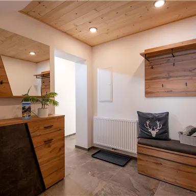 Ein moderner Eingangsbereich mit Holzmöbeln und einer großen Spiegel. Der Raum bietet eine freundliche Atmosphäre mit viel natürlichem Licht.