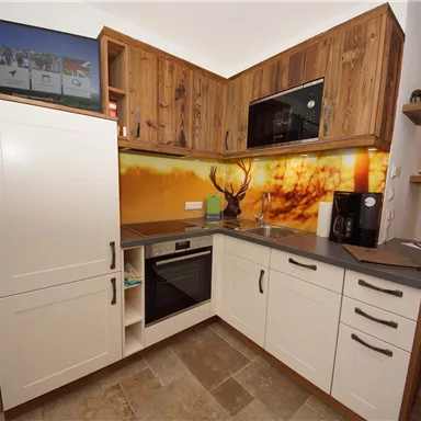 Eine moderne Küche mit Holzoberflächen und einer stilvollen Theke. Die Wand ist mit einem lebendigen Bild und einer Mikrowelle ausgestattet.