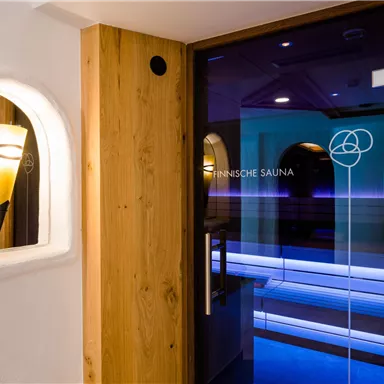 Ein moderner Saunabereich mit einer Glastür und stilvollem Holzdesign. Sanfte Beleuchtung sorgt für eine entspannende Atmosphäre.