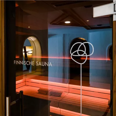 Ein Eingang zu einer finnischen Sauna mit moderner Beleuchtung. Die Atmosphäre ist einladend und entspannend.
