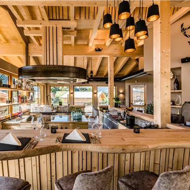 Ein modernes Restaurant mit Holzinterieur und großen Fenstern. Die Bar ist stilvoll eingerichtet und bietet einen Blick auf die Umgebung.