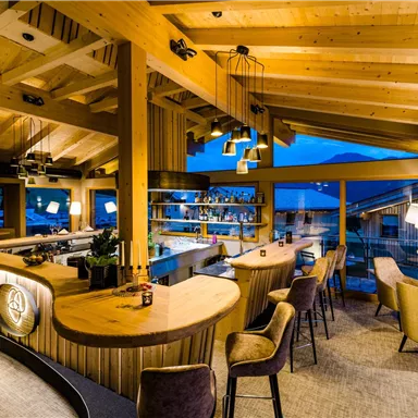 Eine stilvolle Bar mit Holzdekor und modernen Möbeln. Große Fenster bieten einen Blick auf die Umgebung.