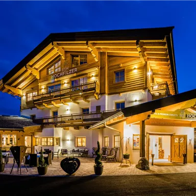 Ein gemütliches Holzhaus mit warmem Licht bei Nacht. Die Architektur ist traditionell und einladend, umgeben von einer malerischen Landschaft.