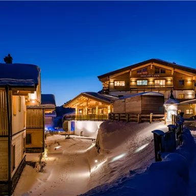 Ein wunderschönes Chalet in einer winterlichen Landschaft bei Nacht. Der Schnee und die warmen Lichter schaffen eine gemütliche Atmosphäre.