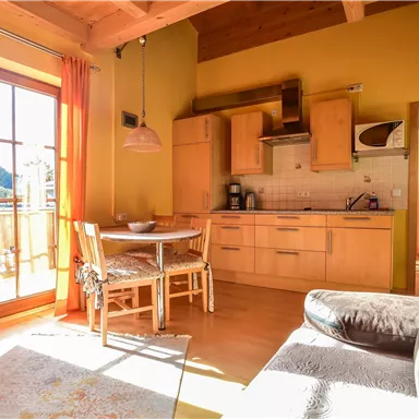 Eine gemütliche Wohnung mit einer modernen Küche und einem Essbereich. Große Fenster lassen viel Licht herein und bieten Aussicht auf die Natur.