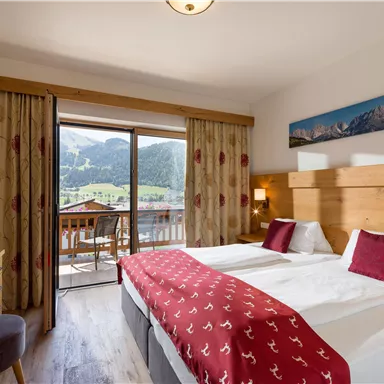 A cozy hotel room with two beds and a beautiful view of the mountains. The terrace offers an inviting way to enjoy nature.