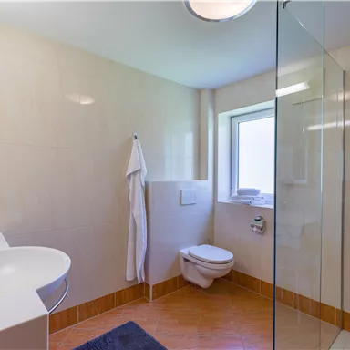 A modern bathroom with a shower and a sink. The room has bright tiles and plenty of natural light.