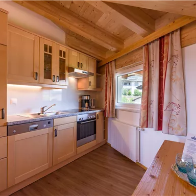 A modern kitchen with wooden cabinets and stainless steel appliances. Large window view and cozy dining area.