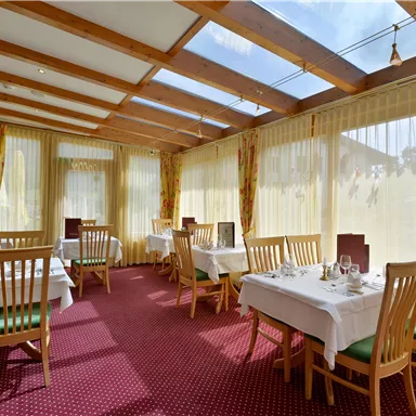 A bright restaurant with large windows and wooden beams. The tables are elegantly set and invite you to linger.