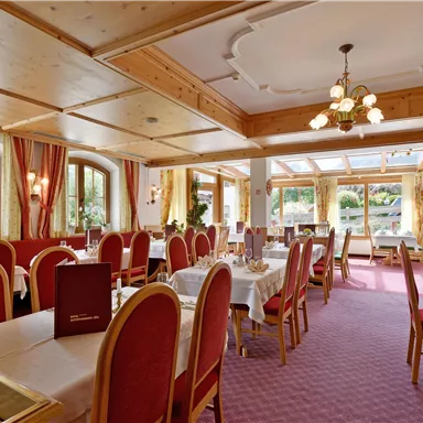 A cozy restaurant with wooden decor and red chairs. Large windows provide a beautiful view of the surroundings.