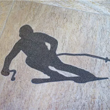 A stylized skier is depicted on the ground. The silhouette shows a dynamic skiing position.