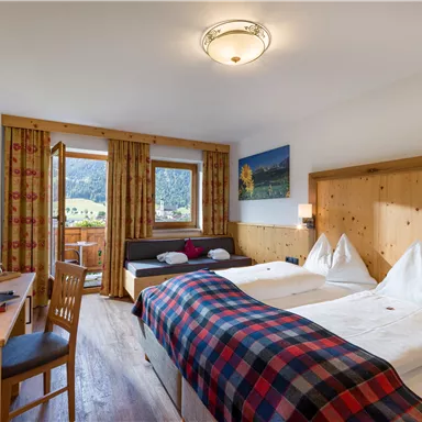 Cozy double room with wooden furniture, checkered details, and a balcony with mountain view.