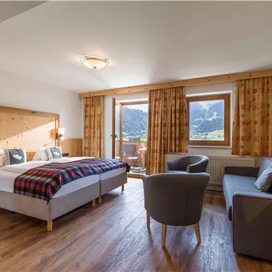 Spacious double room at Hotel Alpenpanorama in the Wilder Kaiser holiday region with seating area, sofa, desk, and plenty of daylight.