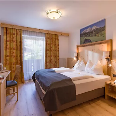 Double room at Hotel Alpenpanorama in the Wilder Kaiser holiday region with wooden accents, desk, and elegant lighting conce