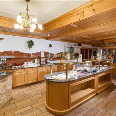 Bright restaurant area at Hotel Alpenpanorama with buffet station, wooden ceiling, and Tyrolean-style furnishings.