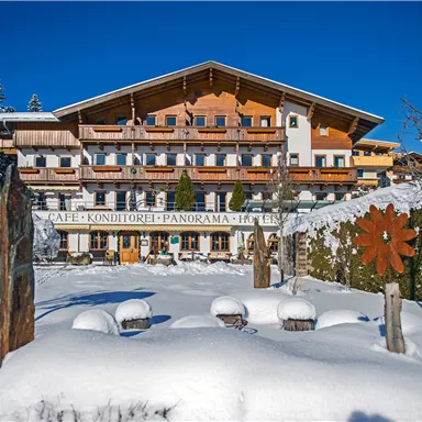 A charming building in Alpine style, surrounded by snow-covered landscapes. The clear blue sky complements the wintry scenery.