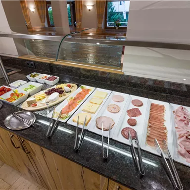 Ein reichhaltiges Büfett mit verschiedenen Käsesorten, Aufschnitt, frischem Gemüse und Salaten. Es bietet eine bunte Auswahl für ein leckeres Frühstück.