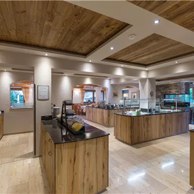 Ein modernes Buffet-Restaurant mit Holzregalen und hellem Licht. Die Tische sind für Gäste vorbereitet und bieten eine einladende Atmosphäre.