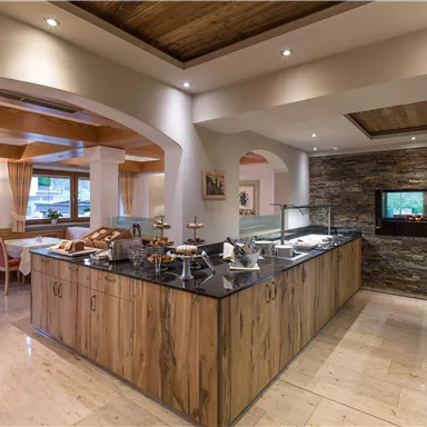 Ein elegantes Restaurant mit einer Holztheke und einem Buffetbereich. Gemütliche Tischanordnung und warmes Licht schaffen eine einladende Atmosphäre.